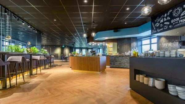 Modern ingerichte eetruimte aan de George Hintzenweg met houten vloer, buffetmeubels en hoge zitplekken.